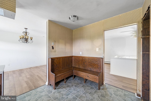 interior space featuring baseboards, a baseboard heating unit, wood finished floors, and ceiling fan with notable chandelier