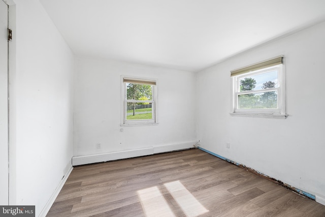 empty room featuring baseboards, baseboard heating, and wood finished floors