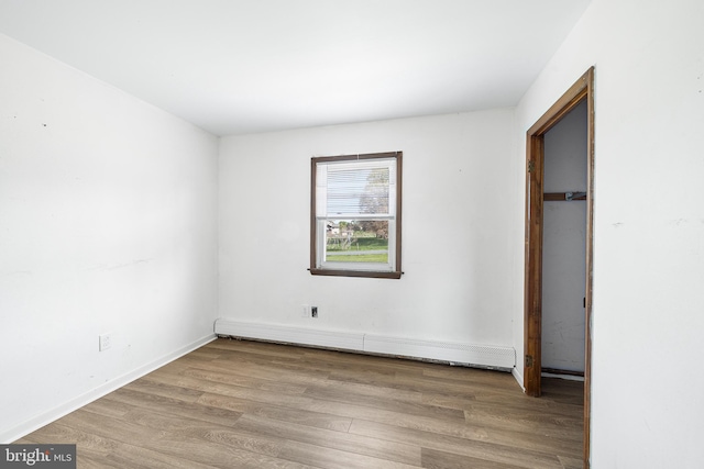 unfurnished bedroom with baseboards, a baseboard radiator, and wood finished floors