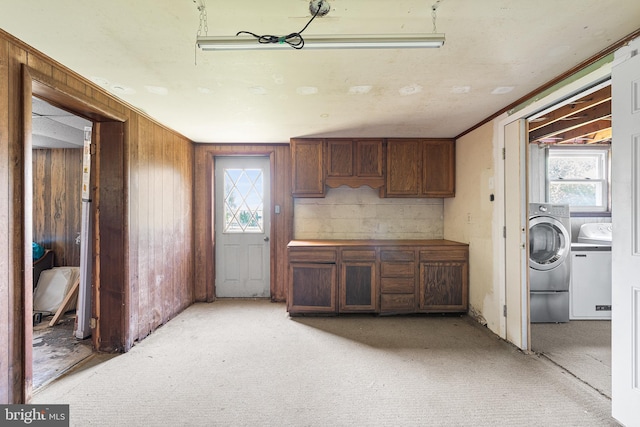 kitchen featuring separate washer and dryer, wood walls, light colored carpet, and a wealth of natural light