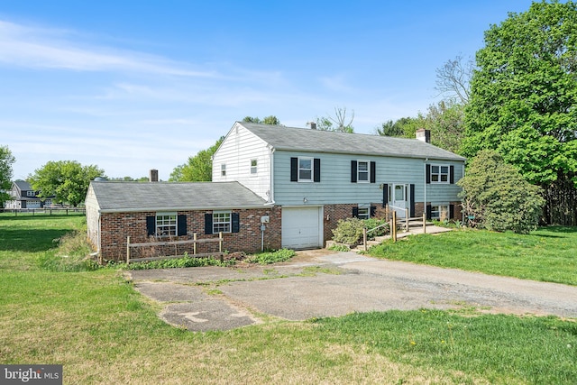 bi-level home featuring an attached garage, brick siding, a front yard, a chimney, and driveway