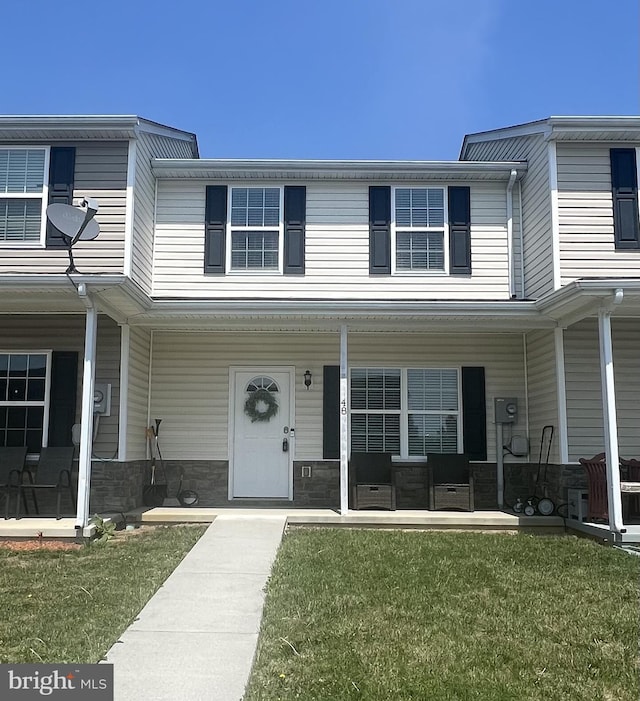 view of front of house with covered porch, stone siding, and a front yard