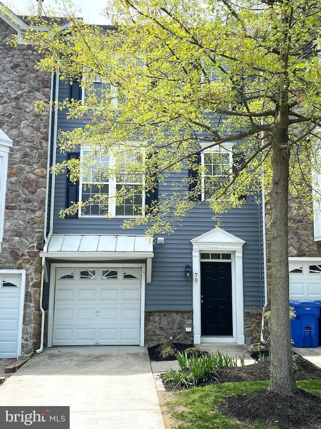 view of front facade featuring a garage, driveway, and stone siding