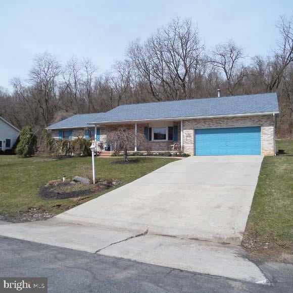 ranch-style home with an attached garage, a front lawn, and driveway