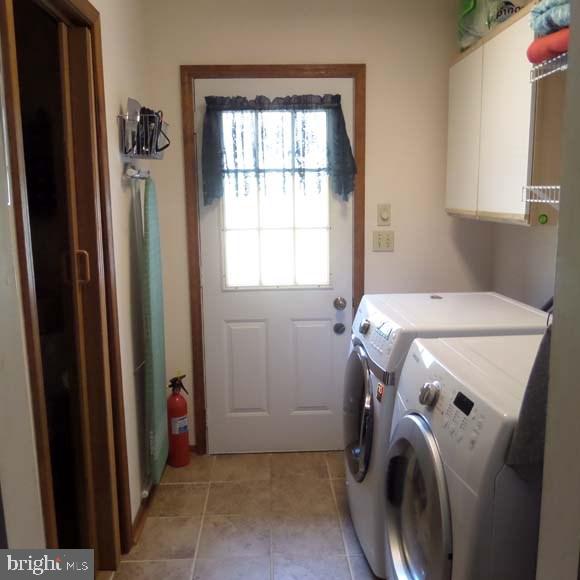 laundry area featuring cabinet space, light tile patterned floors, and washer and dryer