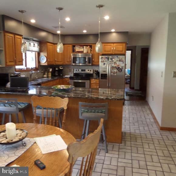 kitchen featuring baseboards, a sink, appliances with stainless steel finishes, and brown cabinets