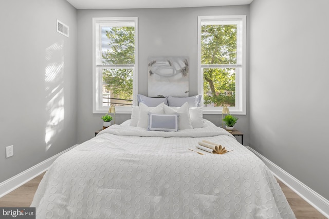 bedroom with baseboards, wood finished floors, and visible vents