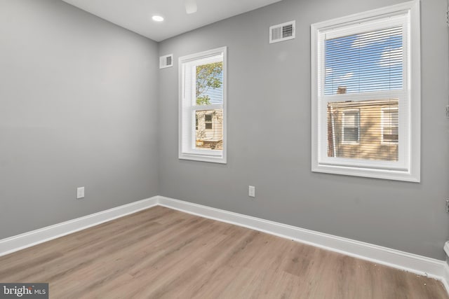 empty room with baseboards, light wood-type flooring, and visible vents