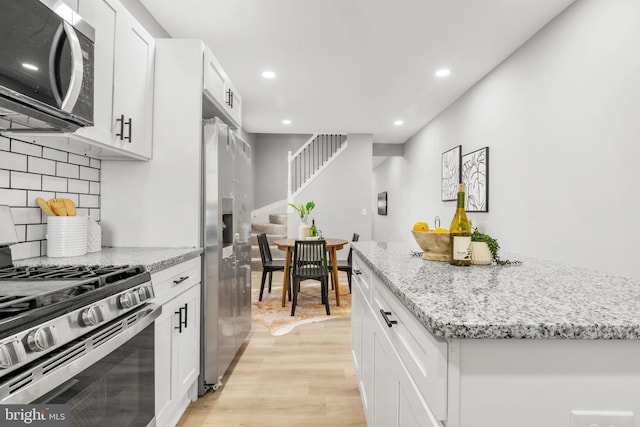 kitchen featuring a center island, light wood-type flooring, white cabinets, stainless steel appliances, and recessed lighting