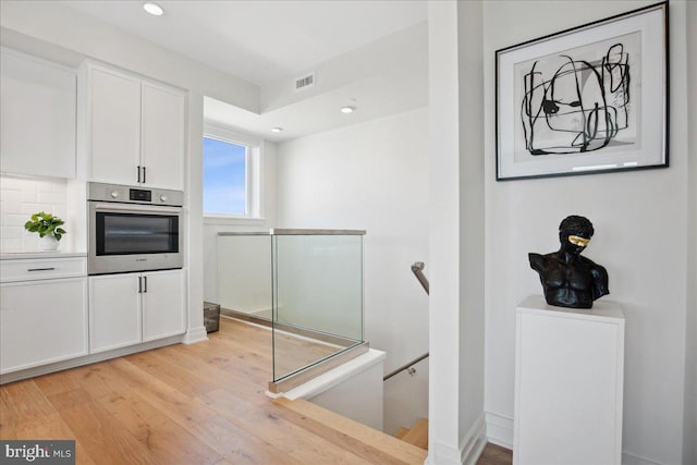 923 V St NW Unit 601, Washington, DC 20001 - kitchen with stainless steel oven, white cabinetry, light wood-style flooring, recessed lighting, and light countertops