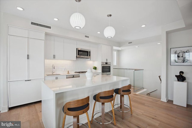 923 V St NW Unit 601, Washington, DC 20001 - kitchen featuring appliances with stainless steel finishes, white cabinets, backsplash, a breakfast bar, and recessed lighting