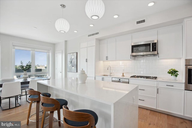 923 V St NW Unit 601, Washington, DC 20001 - kitchen featuring appliances with stainless steel finishes, backsplash, a center island, white cabinets, and recessed lighting