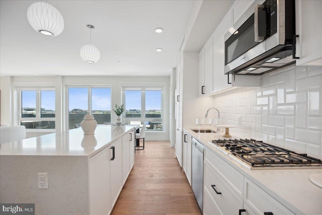 923 V St NW Unit 601, Washington, DC 20001 - kitchen featuring stainless steel appliances, light wood-style floors, tasteful backsplash, white cabinets, and a center island