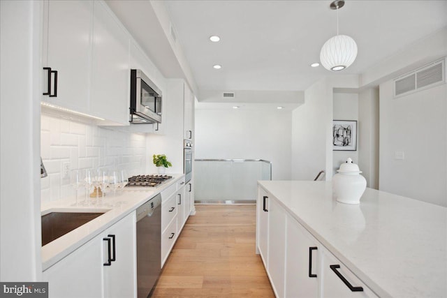 923 V St NW Unit 601, Washington, DC 20001 - kitchen with stainless steel appliances, tasteful backsplash, white cabinetry, light wood-type flooring, and recessed lighting