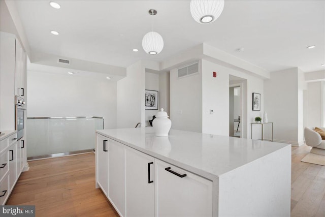 923 V St NW Unit 601, Washington, DC 20001 - kitchen with stainless steel oven, white cabinets, light wood-style floors, recessed lighting, and a kitchen island