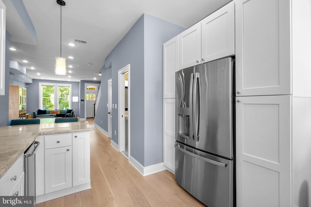 kitchen featuring stainless steel fridge, recessed lighting, white cabinetry, open floor plan, and baseboards