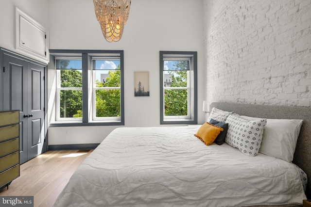 bedroom featuring a chandelier, a high ceiling, and light wood finished floors