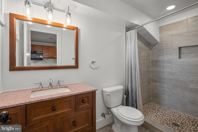 bathroom featuring tiled shower, toilet, and vanity