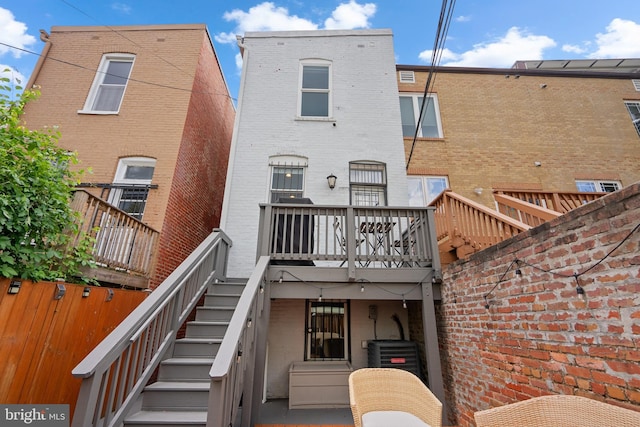 back of property featuring stairs, brick siding, and central air condition unit