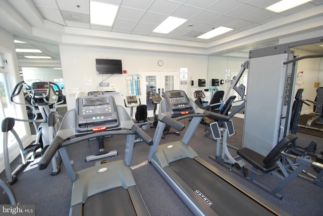 gym with a paneled ceiling and a tray ceiling