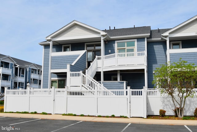 view of front facade featuring a porch, a fenced front yard, a gate, stairway, and uncovered parking