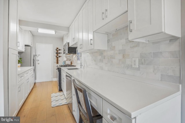 4201 Cathedral Ave NW Unit 616W, Washington, DC 20016 - kitchen featuring light countertops, white cabinets, decorative backsplash, and stainless steel appliances