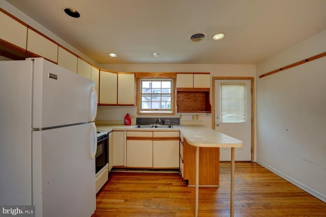 kitchen featuring freestanding refrigerator, a sink, range with electric cooktop, light countertops, and recessed lighting
