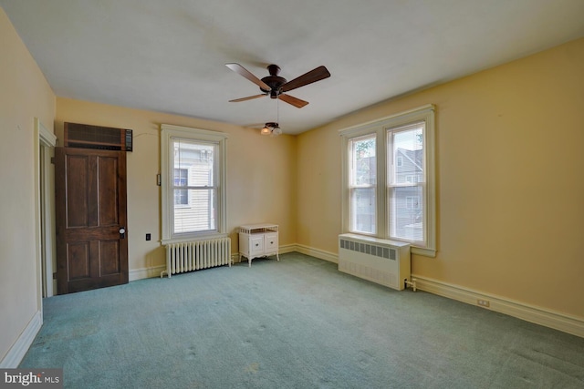 carpeted empty room with radiator heating unit, radiator, ceiling fan, an AC wall unit, and baseboards
