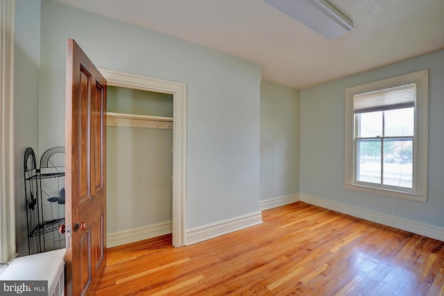 unfurnished bedroom featuring light wood-style floors, baseboards, and a closet