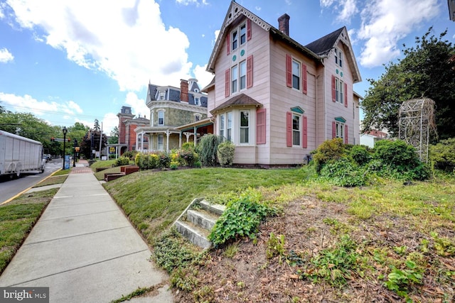 view of side of property featuring a chimney and a yard