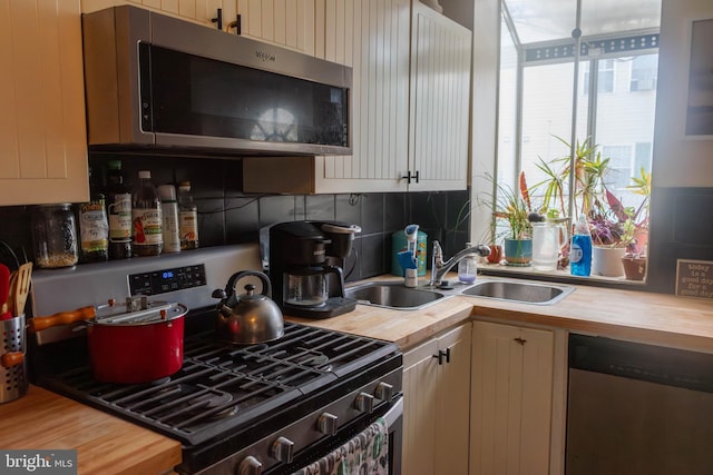 kitchen featuring wooden counters, stainless steel appliances, tasteful backsplash, and a sink