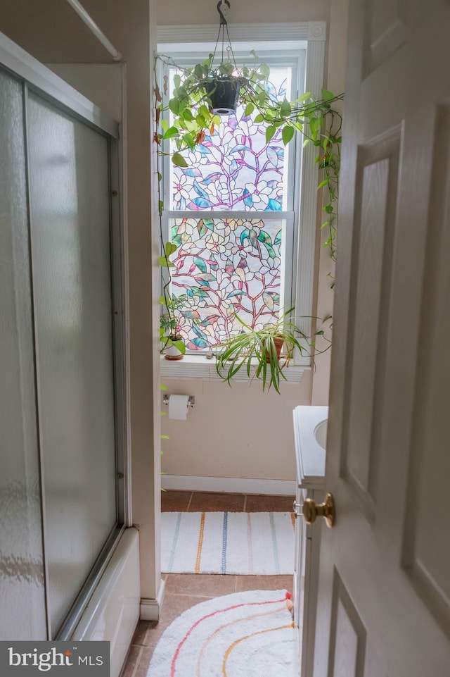 bathroom featuring a shower with door, tile patterned flooring, and baseboards