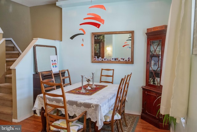 dining area with baseboards, stairway, and wood finished floors