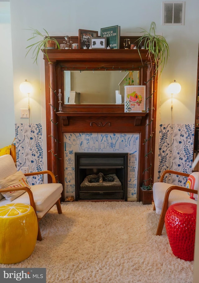 sitting room featuring a tile fireplace, visible vents, and carpet floors