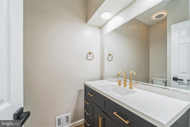bathroom featuring visible vents, toilet, and vanity