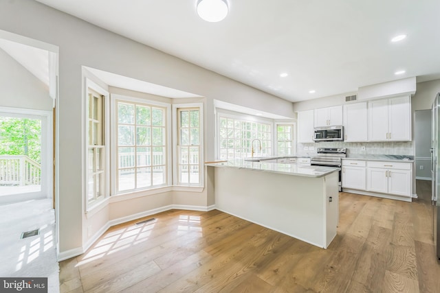 kitchen featuring visible vents, appliances with stainless steel finishes, tasteful backsplash, and light wood-type flooring