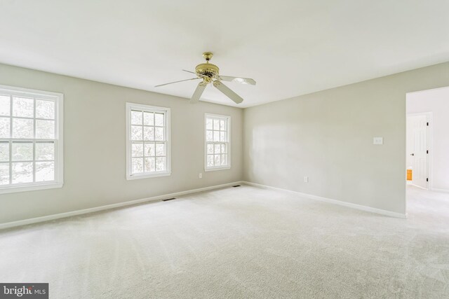 carpeted empty room featuring baseboards, ceiling fan, and visible vents