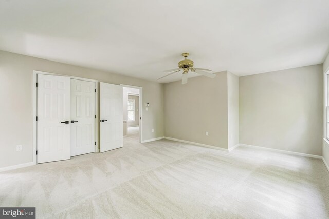 interior space featuring baseboards, ceiling fan, light carpet, and a closet
