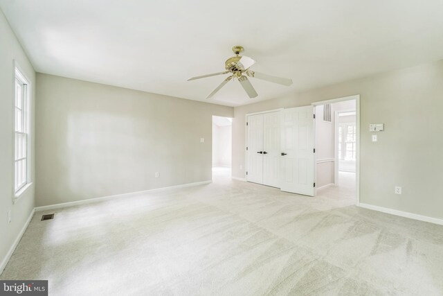 unfurnished bedroom with baseboards, ceiling fan, light carpet, and visible vents