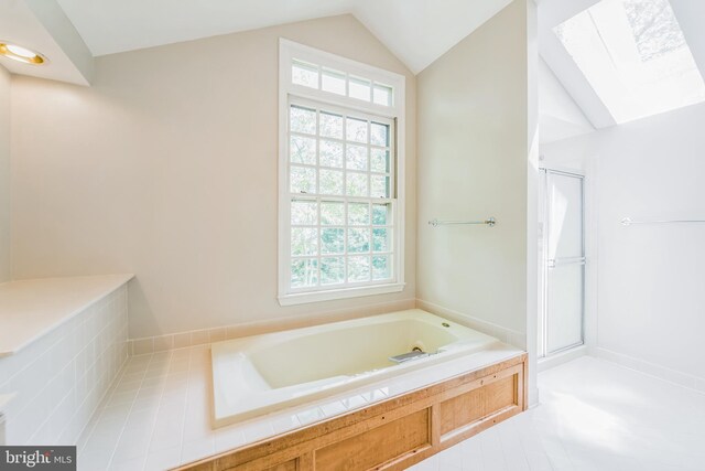 full bathroom with vaulted ceiling with skylight, a shower stall, and a garden tub