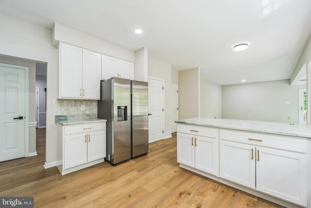 kitchen featuring tasteful backsplash, white cabinetry, light stone counters, stainless steel fridge, and light wood-style flooring