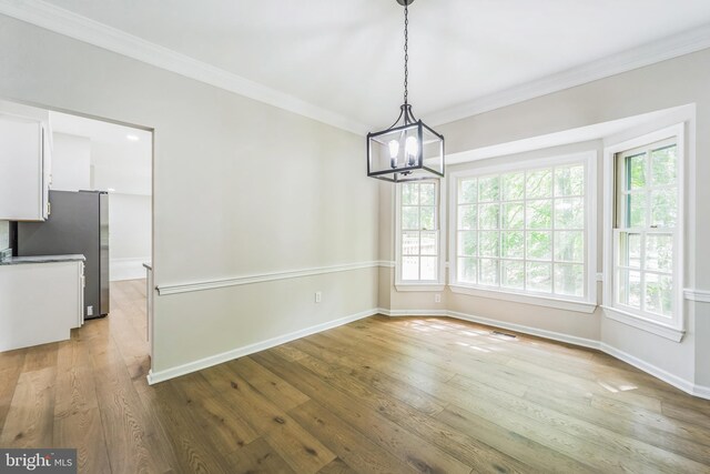 unfurnished dining area featuring plenty of natural light, ornamental molding, baseboards, and a notable chandelier