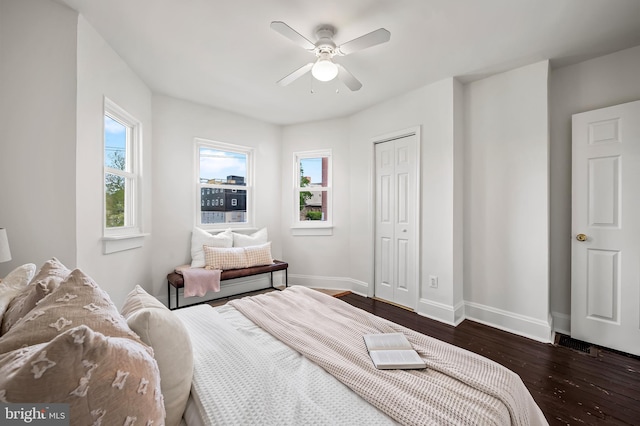 bedroom with baseboards, ceiling fan, a closet, and dark wood-type flooring