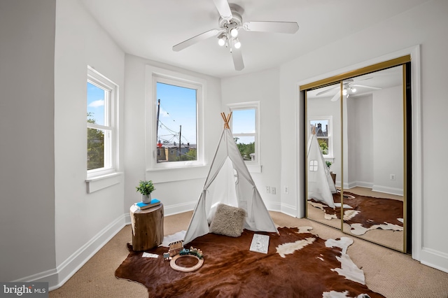 rec room featuring a ceiling fan, baseboards, and carpet