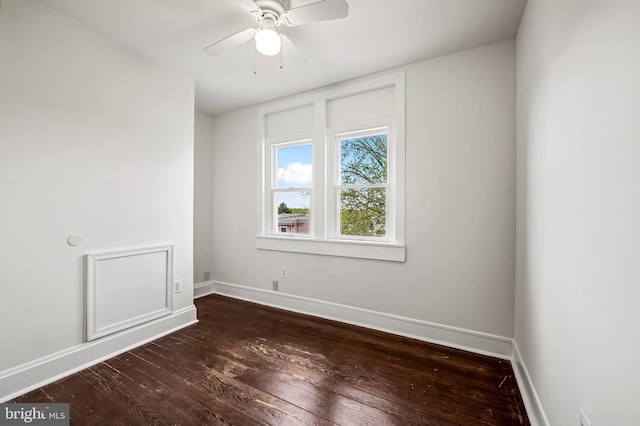 empty room with baseboards, a ceiling fan, and dark wood-style flooring