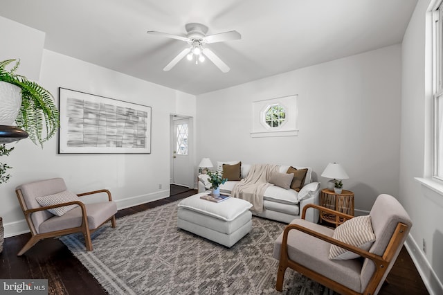 living room featuring baseboards, a ceiling fan, and wood finished floors