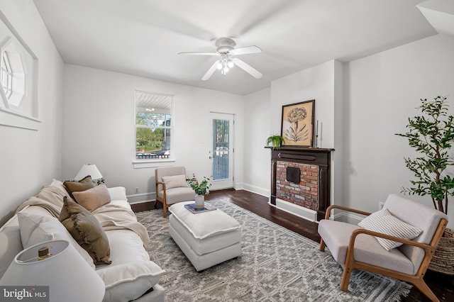 living room featuring baseboards, ceiling fan, a fireplace, and wood finished floors