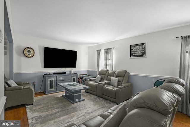 living area with wood finished floors and a wainscoted wall