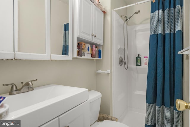 full bathroom featuring a sink, a stall shower, and toilet