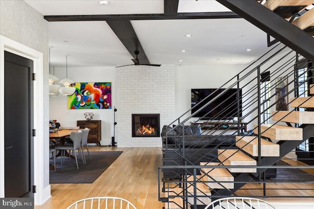 stairs featuring recessed lighting, beam ceiling, wood finished floors, and a fireplace
